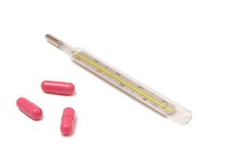 Glass thermometer with three magenta pills isolated on white