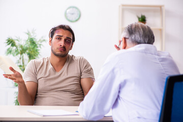 Obraz premium Young face injured man visiting experienced male doctor traumato