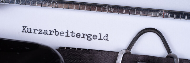 Kurzarbeitergeld, geschrieben auf einer alten Schreibmaschine. Panorama