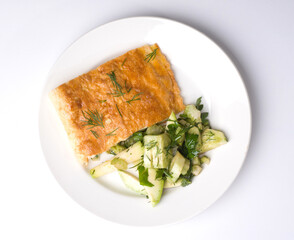 Omelet and fresh cucumber salad. Appetizing breakfast on a white round plate. Top view