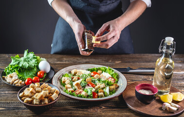 Chef is grating the cheese into an appetizing fresh salad. Concept of cooking delicious Caesar