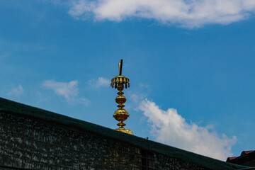 Brass Kalash on top of Gurudwara with blue sky and clouds in background..