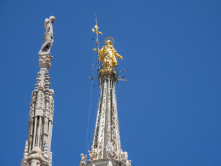 Fototapeta na wymiar Milano, Italy. The famous Madonnina in gilded copper and placed on the main spire of the cathedral of Milan. A statue of the Virgin Mary. One of the main symbol of the city of Milan