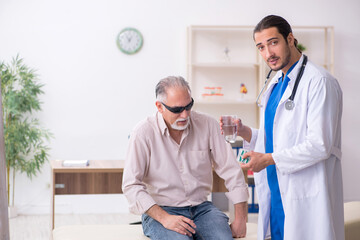 Fototapeta premium Old blind man visiting young male doctor