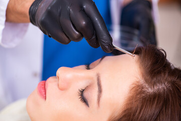 Naklejka premium Young woman visiting male beautician in hair transplantation con