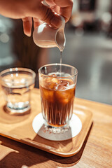 Urban style coffee shop with wood and glass window decoration open space hand pouring syrup into coffee