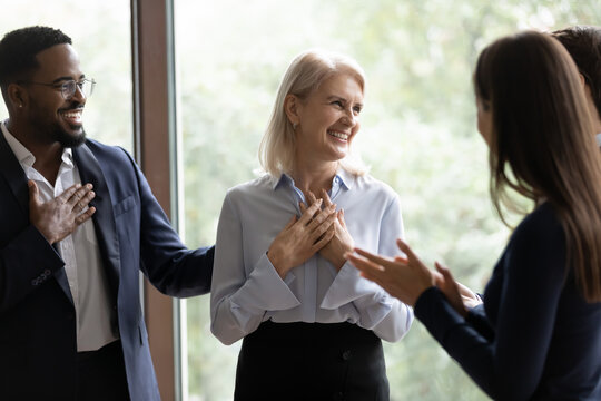 60s businesswoman staff member get praises congrats cheers compliments from multi ethnic colleagues. Promotion career advance, life events birthday celebration, warm relation, kindness from teammates