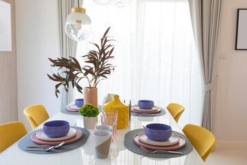 Beautiful table setting with pink and purple plate on table. Glassware and cutlery for catered event dinner.