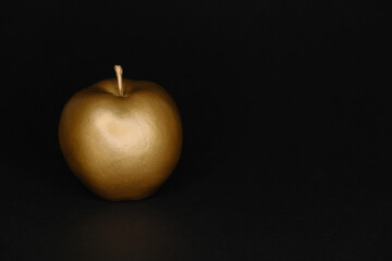 Golden apple on a black background, art deco fruit.