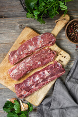 Lamb meat. A young lamb on a wooden Board on a gray wooden kitchen table. Lamb meat and cooking ingredients. The view from the top