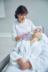 Concentrated skilled beautician using effective medical instrument
