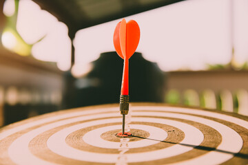 Bullseye or dart board has dart arrow throw hitting the center of a shooting target with sunshine...