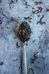 Herbal tea in spoon. Spoon with dry tea leaves. Tea on a concrete background