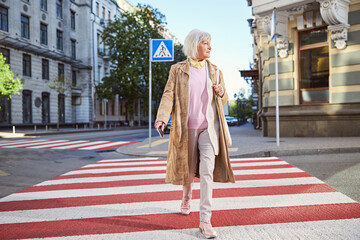 Senior good looking Caucasian woman walking the street in old city