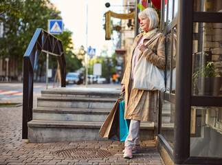 Obraz premium Senior Caucasian woman strolling on city street after shopping