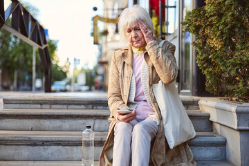 Fototapeta premium Portrait of an attractive senior woman sitting on a steps