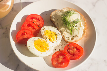 Delicious breakfast on the table. Boiled eggs, tomatoes, cream cheese sandwich, dill on a plate