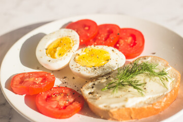 Delicious breakfast on the table. Boiled eggs, tomatoes, cream cheese sandwich, dill on a plate