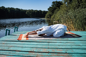a young girl does yoga on a lake on a Sunny summer day, meditation, relaxing pose, solitude in nature, peace, relaxation, asana, healthy lifestyle, life style, Zen