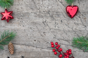 Merry Christmas greeting card. Red christmas decorations, fir twigs and holly berries on old wooden...