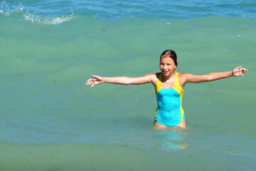 girl with hands up smiling at sea