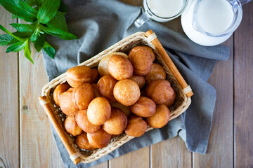 Delicious doughnuts in a wicker basket on a wooden table. The view from the top