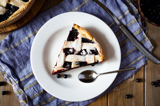 A piece of blueberry pie on a white plate top view