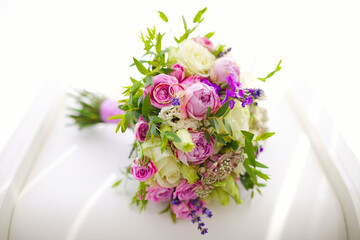 Close up of golden wedding rings of young and fresh flower bouquet of roses and other blooming beautiful flowers