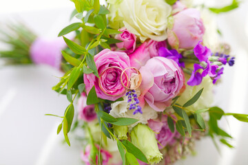 Close up of golden wedding rings of young and fresh flower bouquet of roses and other blooming beautiful flowers