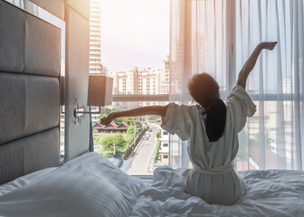 Hotel room comfort with good sleep easy relaxation lifestyle of Asian girl on bed have a nice day morning waking up, taking some rest, lazily relaxing in guest bedroom in city hotel - obrazy, fototapety, plakaty