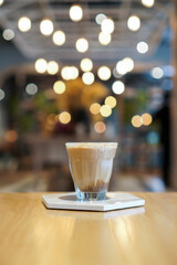 Piccolo Latte, a cup of espresso shot with skimmed milk served in cold coffee on wooden table with blurred background. Center Focus.