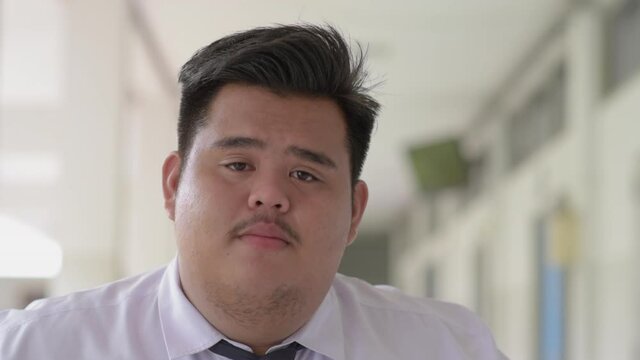 A fat Asian man wearing an office suit and wearing a necktie and a white shirt, looks sad and disappointed to cry.