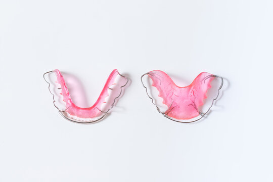 hawley retainer on white background. pink retainer teeths for dental patient.