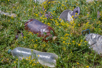 Close-up of discarded plastic bottles in a beautiful meadow among flowers. Plastic pollution in Danube Biosphere Reserve. Plastic garbage environmental pollution problem.