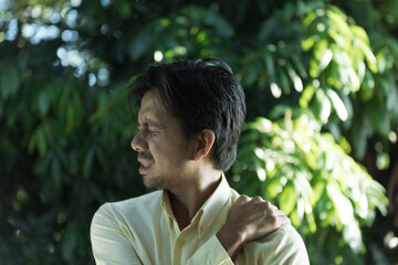 young asian man feeling the pain in shoulder