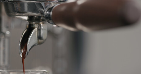 pulling espresso shot with single spout portafilter from coffee machine closeup