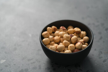 roasted hazelnuts in black bowl on terrazzo countertop