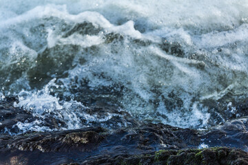 Closeup of moving ocean water with foam and small waves caused by wind and rain seen from a boat