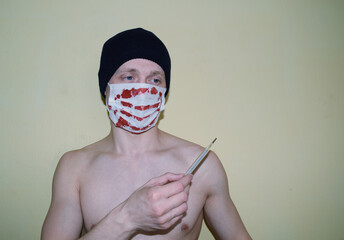 Young naked man in a hat in a medical mask with a thermometer in his hand