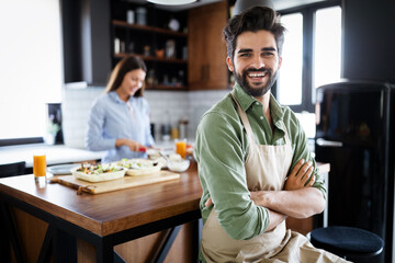 Fototapeta premium Portrait of happy young couple cooking together in the kitchen at home.