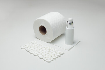 Toilet paper, disinfectant gel, and medications on a white table. Hygiene, protection, and treatment. A concept of personal hygiene and prevention.
