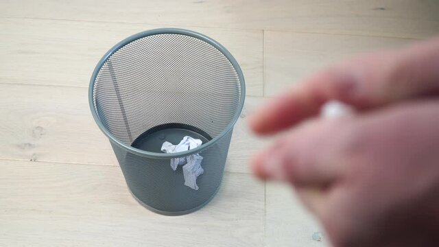 Office employee tossing away crumpled paper into trash can