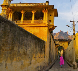 Indian woman walking along city walls of Jagat Shiromani Hindu Temple in Amber near Jaipur in...