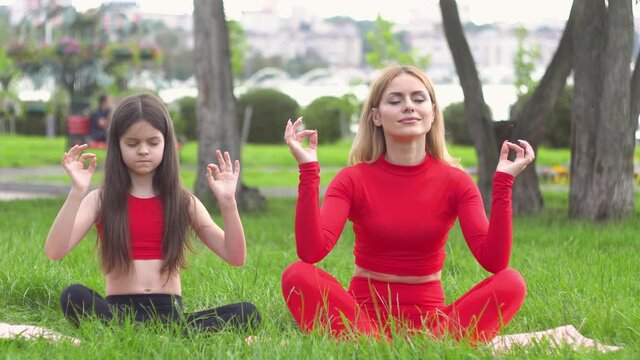 Woman with daughter enjoying yoga in the park. Healthy lifestyle concept