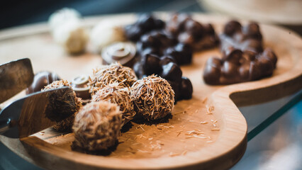 Wooden heart presentation plate chocolate presentation. round chocolates close up