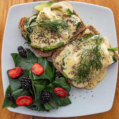 Eggs benedictine on slices of box bread, salmon, avocado and topped with a hollandaise sauce with...
