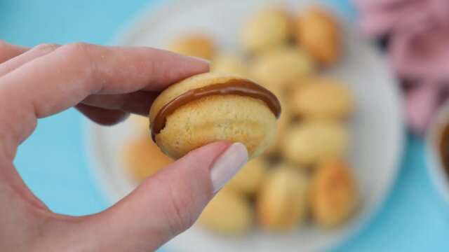 Homemade cookies stuffed with caramel or dulce de leche. Female hand holding a cookie with caramel filling