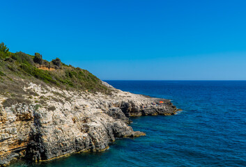 Beautiful rocky Cliffs with people on boats in Kamenjak National Park, Istria, Croatia