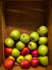 Red and green apples in a wooden case, ready for selling in grocery. Wooden crate box full of fresh apples. Copy space available.