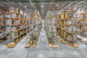 Large industrial warehouse. Tall racks are completely filled with boxes and containers.